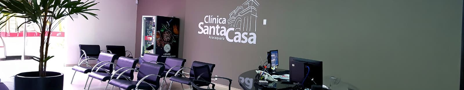 Recepção da Santa Casa de Araraquara, com poltronas de espera e identidade visual da Clínica Santa Casa na parede